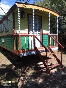 une petite maison verte avec une terrasse couverte et un escalier dans l'établissement Le Mas d'Icard, à Saintes-Maries-de-la-Mer