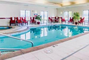 a large swimming pool in a hotel with red chairs at Comfort Suites Helena Airport in Helena