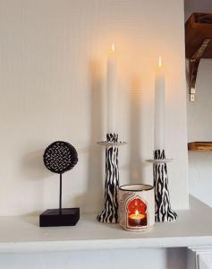 根特的住宿－Enchanting Moroccan Getaway，架子上有两个白色的蜡烛和一个蜡烛架