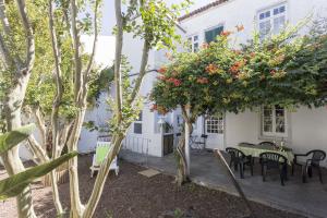 Casa blanca con mesa, sillas y árboles en Family House Garden, en Ponta Delgada