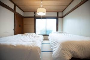 2 camas en una habitación con ventana en 【70平米 長期予約大歓迎】6LDK/日本家屋貸切/大人数で寛げる空間, en Tokio