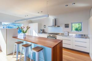 a kitchen with white cabinets and a counter with stools at Percy Street I Private Properties in Gracetown