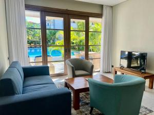 een woonkamer met een bank en stoelen en een tv bij Peninsula Bay Resort in Nusa Dua