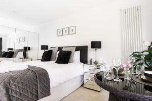 a white bedroom with two beds and a table at Boswenna in St Ives