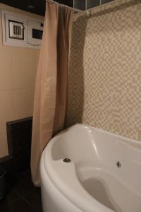 La salle de bains est pourvue d'une baignoire blanche et d'un rideau de douche. dans l'établissement Modern Loft in the city center of Levadia, Greece, à Lébadée