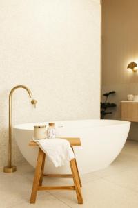 a bathroom with a white bath tub and a wooden stool at White House Swan Hill in Swan Hill