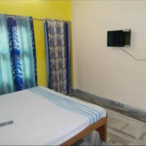 Cama pequeña en habitación con cortinas coloridas en GRG K.S.N. PAYING GUEST HOUSE, en Varanasi