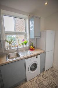 Il comprend une cuisine équipée d'un évier et d'un lave-linge. dans l'établissement Hammersmith Apollo 1 Bedroom Apartment, à Londres