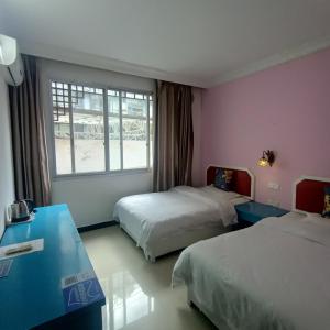 Habitación de hotel con 2 camas y ventana en Yangshuo How Flowers Hostel en Yangshuo