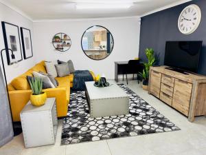 ein Wohnzimmer mit einem gelben Sofa und einem TV in der Unterkunft Lemon Ivy Guesthouse in Polokwane