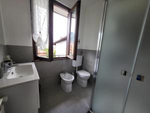 een badkamer met een toilet, een wastafel en een raam bij Sophia Apartment in Gravellona Toce