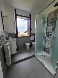 een badkamer met een douche, een toilet en een raam bij Sophia Apartment in Gravellona Toce