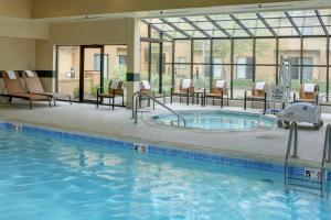 a pool in a hotel with chairs and a swimming pool at Courtyard by Marriott Indianapolis Airport in Indianapolis