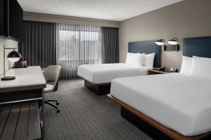a hotel room with two beds and a desk at Courtyard Jacksonville Butler Boulevard in Jacksonville