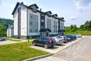 un gran edificio con coches estacionados en un estacionamiento en Apartament Boho en Ustrzyki Dolne