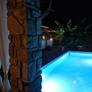 a swimming pool at night next to a stone wall at Andrea Villa Keszthely in Keszthely