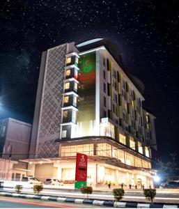 a large building with a sign on it at night at Grand Safran Hotel Pangkalpinang in Pangkalpinang