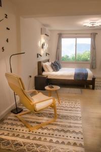een slaapkamer met een bed, een stoel en een raam bij הבית ליד הבוסתן דירה לזוג in Mikhmannim