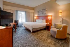 a hotel room with a bed and a flat screen tv at Courtyard Memphis Germantown in Memphis