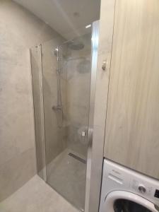 a shower with a glass door next to a washing machine at Bagry Rooms3 LoveKrakow in Kraków