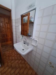 Baño blanco con lavabo y espejo en Cycladic House in Paros en Márpissa