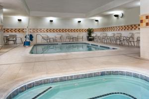 una piscina en una habitación de hotel con mesas y sillas en Courtyard Memphis Collierville, en Collierville
