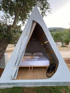 Spasméni Vrísi的住宿－Nirikos Camping，树下的白色帐篷内的一张床位