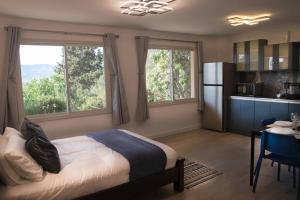 een slaapkamer met een bed en een keuken met ramen bij הבית ליד הבוסתן דירה לזוג in Mikhmannim