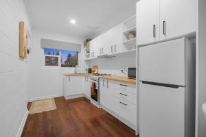 a kitchen with white cabinets and a refrigerator at Perfect Cosy Beachside Escape in Grange