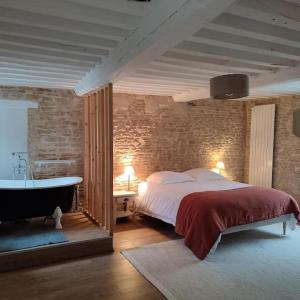 a bedroom with a large bed and a bath tub at Charmante maison de pêcheur in Saint-Aubin-sur-Mer