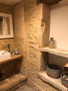 uma casa de banho com um lavatório e uma parede de pedra em Charmante maison de pêcheur em Saint-Aubin-sur-Mer