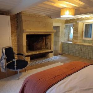 a room with a fireplace with a bed and a chair at Charmante maison de pêcheur in Saint-Aubin-sur-Mer