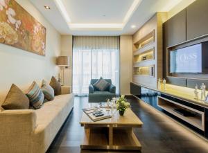 a living room with a couch and a tv at Qiss Residence by Bliston - SHA Plus in Bangkok