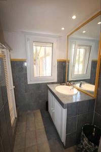 ein Bad mit einem Waschbecken und einem Spiegel in der Unterkunft FACE à la Mer, Superbe appartement climatisé au RDC d'une maison, classé 4 étoiles, 5 couchages -WIFI-PORTIRAGNES PLAGE LXBFM32 in Portiragnes