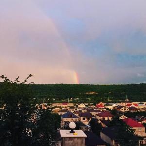 a rainbow in the sky over a town with houses at Fraish air boutige in Qusar