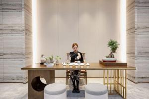 Holiday Inn Taiyuan City Center في تاييوان: امرأة تجلس في مكتب في غرفة