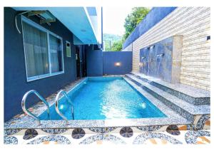 - une piscine à côté d'un bâtiment avec une maison dans l'établissement Sunflower Villa, à Lonavala