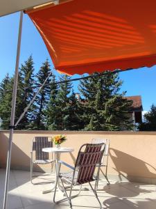 two chairs and a table under an umbrella on a patio at Apartman Bor in Livno