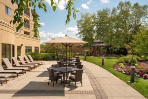 un patio con mesas, sillas y una sombrilla en Courtyard by Marriott Middletown Goshen, en Middletown