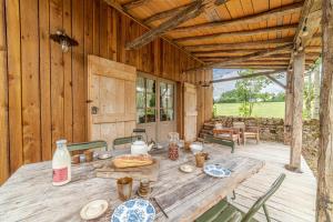een houten tafel op een veranda van een hut bij Colombier - Charmante maison avec jardin 