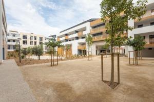 a courtyard with trees in front of a building at Le Corinthe - Appt classé 3 étoiles et climatisé in Marseillan