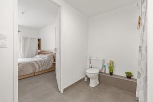 a white bathroom with a toilet and a bed at Le Corinthe - Appt classé 3 étoiles et climatisé in Marseillan