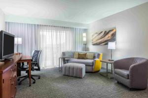 a hotel room with a couch and a desk with a television at Courtyard Knoxville Cedar Bluff in Knoxville