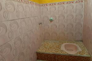 a bathroom with a toilet in the corner of a room at SPOT ON 92857 Kos Haji Jakfar Syariah in Banyuwangi