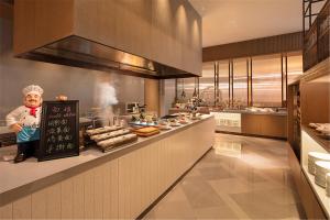 Hilton Garden Inn Xuzhou Yunlong في سوزهو: وجود شيف في مطبخ مع اكل