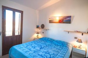 a bedroom with a blue bed and a window at CASA PAU in Porto Ottiolu