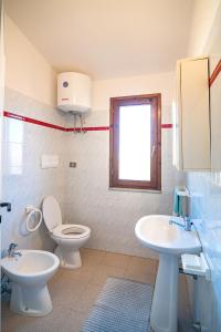 a bathroom with two sinks and a toilet and a window at CASA PAU in Porto Ottiolu +12 photos