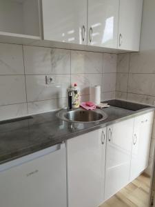 una cucina con lavandino e armadietti bianchi di Bora apartman a Soko Banja