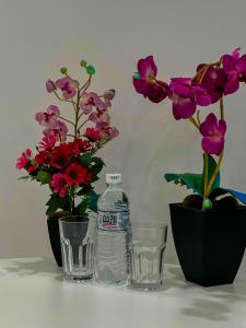 two glasses and a bottle of water next to flowers at Astina Hotel in Astana