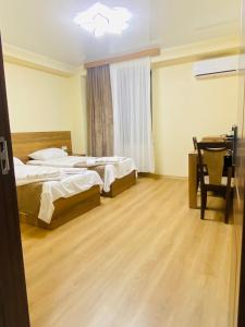 a bedroom with two beds and a table and a window at HOTEL SUNRISE in Kutaisi